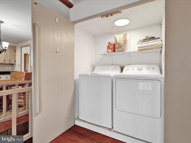 washroom with dark wood-type flooring, a notable chandelier, separate washer and dryer, and laundry area