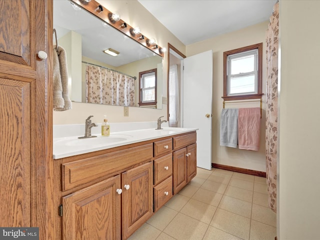 bathroom featuring a sink, baseboards, double vanity, and tile patterned floors