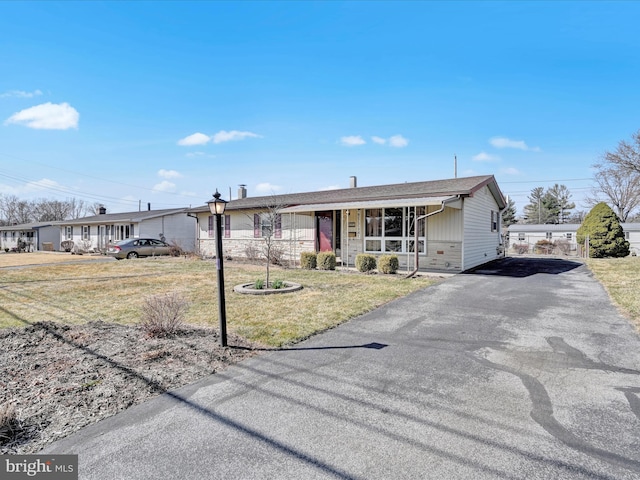 ranch-style home with driveway, covered porch, and a front lawn