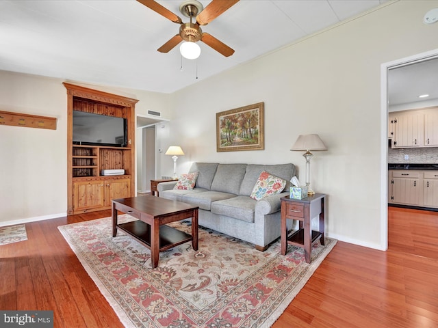 living room with baseboards, light wood-type flooring, and ceiling fan