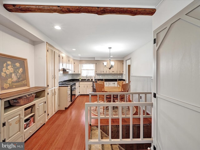 kitchen featuring a sink, dark countertops, gas stove, light wood finished floors, and a chandelier