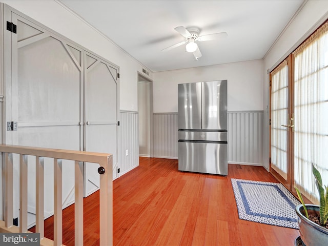 kitchen with light wood-style flooring, wainscoting, freestanding refrigerator, and ceiling fan