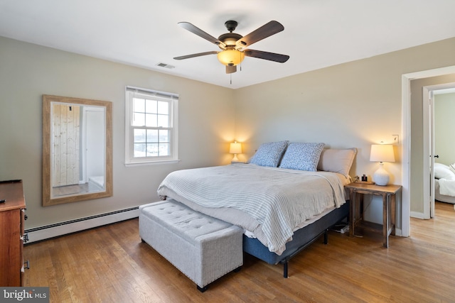 bedroom featuring a ceiling fan, wood finished floors, visible vents, baseboards, and baseboard heating