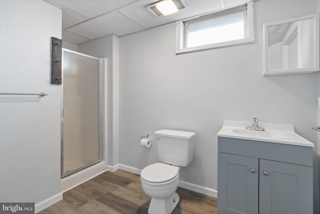 bathroom with toilet, a shower stall, wood finished floors, and a paneled ceiling