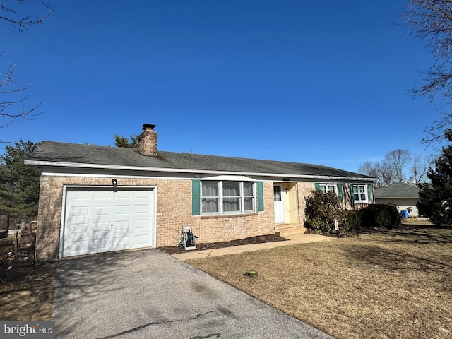 ranch-style house with aphalt driveway, an attached garage, brick siding, and a chimney