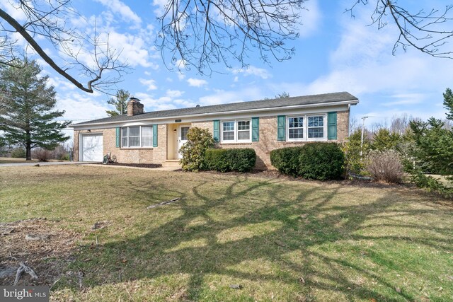 ranch-style house with brick siding, a front yard, an attached garage, and a chimney