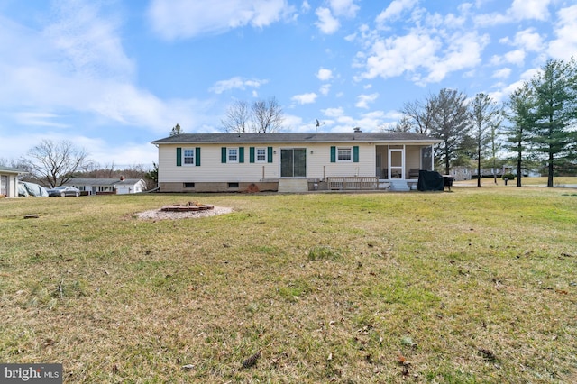 rear view of property featuring a yard, a fire pit, and a sunroom