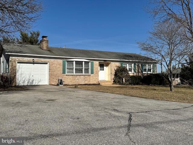 ranch-style house with brick siding, a chimney, aphalt driveway, and a garage