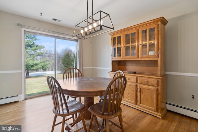 dining area featuring light wood-style floors, baseboards, baseboard heating, and visible vents