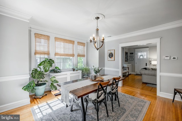 dining area with a notable chandelier, baseboards, light wood finished floors, and ornamental molding