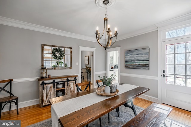 dining room featuring crown molding, light wood-style flooring, and baseboards