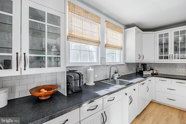 kitchen featuring a sink, backsplash, dark countertops, and dishwasher