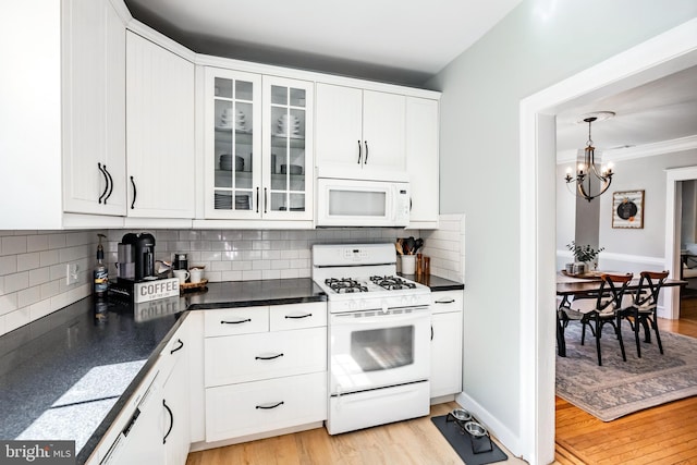 kitchen with white appliances, dark countertops, and white cabinetry