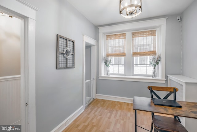 office with light wood-type flooring, baseboards, and a chandelier