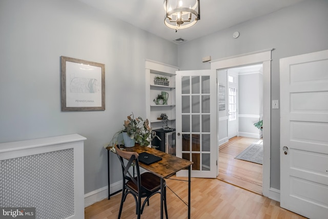 office space with visible vents, light wood-style flooring, baseboards, and an inviting chandelier