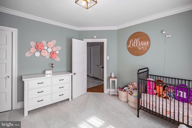 carpeted bedroom with a crib and ornamental molding