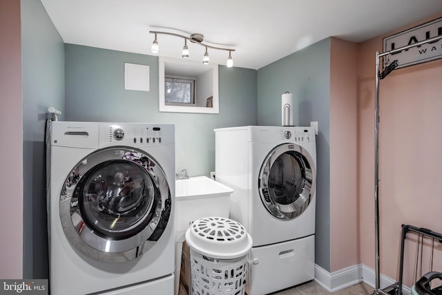 clothes washing area with washing machine and clothes dryer, laundry area, track lighting, and baseboards