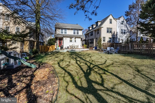 rear view of property featuring a patio area, stucco siding, a lawn, and fence