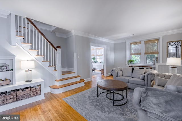 living area featuring stairway, wood-type flooring, baseboards, and crown molding