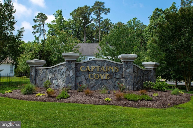 community / neighborhood sign with fence and a lawn