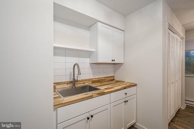 kitchen with a sink, wood counters, open shelves, white cabinetry, and decorative backsplash