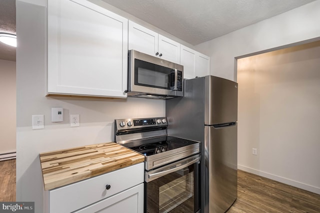 kitchen with white cabinetry, stainless steel appliances, a textured ceiling, and wood finished floors