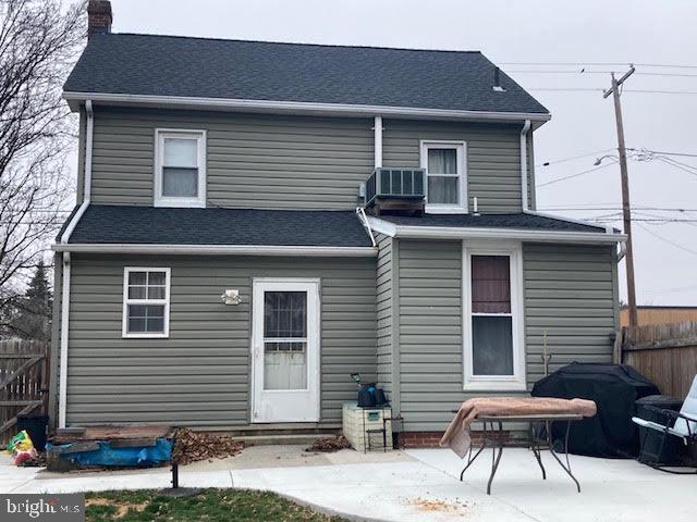 rear view of house featuring a patio area, a chimney, central AC, and fence