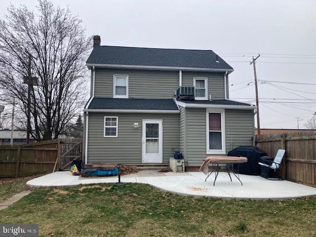 back of property featuring a patio, cooling unit, a fenced backyard, a chimney, and a lawn