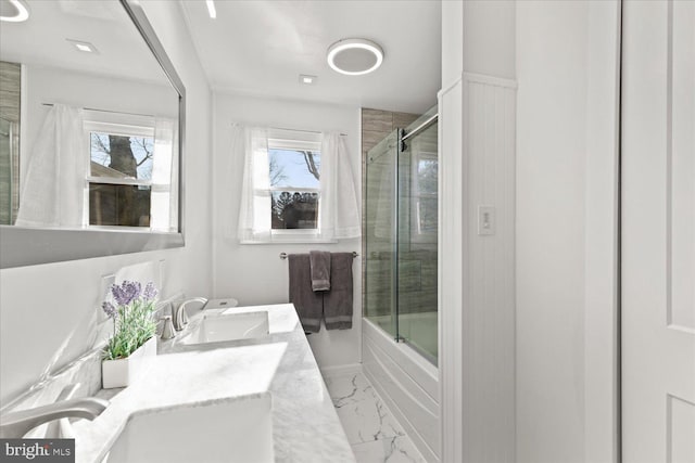 full bath with double vanity, shower / bath combination with glass door, marble finish floor, and a sink