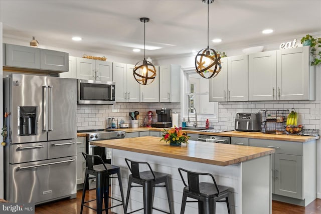 kitchen with a sink, a kitchen breakfast bar, appliances with stainless steel finishes, and wood counters