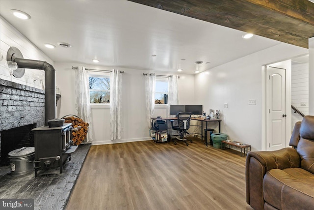 office featuring visible vents, a wood stove, and wood finished floors