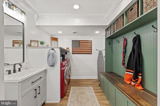 mudroom with a sink, light wood-type flooring, ornamental molding, and washer and dryer