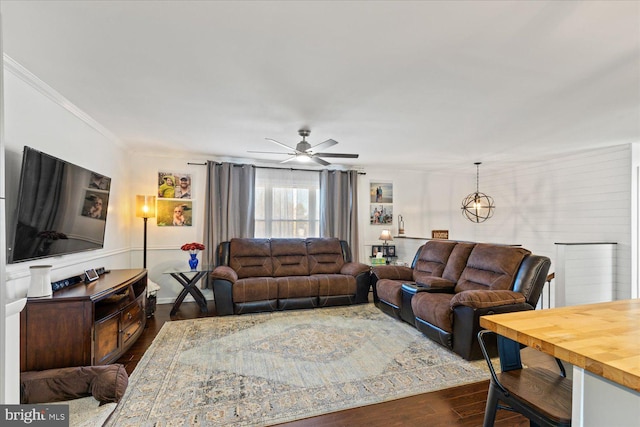 living room with dark wood finished floors, ceiling fan with notable chandelier, and crown molding