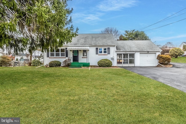 view of front facade with stucco siding, driveway, a front yard, a shingled roof, and a garage