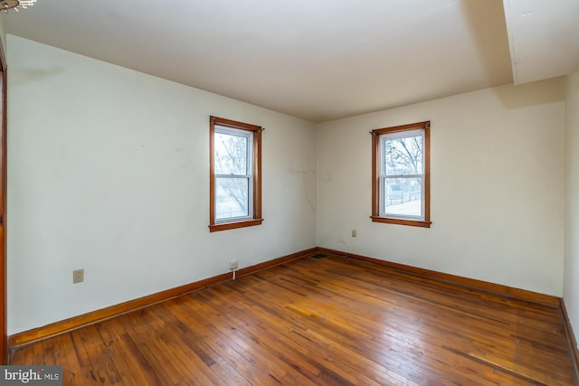 empty room featuring baseboards, a healthy amount of sunlight, and hardwood / wood-style flooring