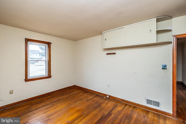 spare room featuring hardwood / wood-style floors, baseboards, and visible vents