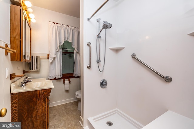 bathroom featuring vanity, toilet, baseboards, and walk in shower