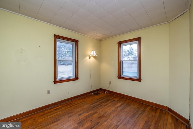 empty room featuring a healthy amount of sunlight, baseboards, and hardwood / wood-style flooring