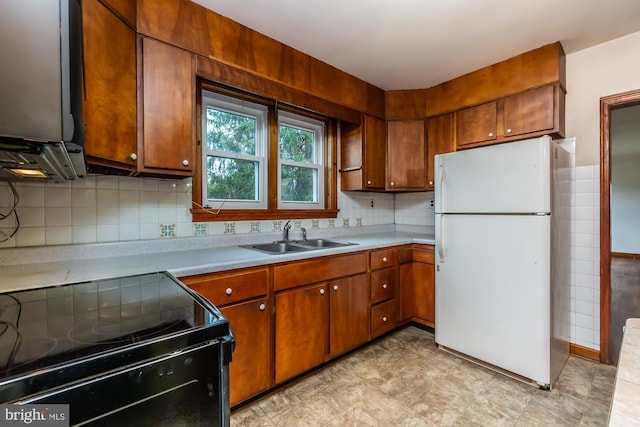 kitchen featuring electric range, freestanding refrigerator, a sink, light countertops, and brown cabinets