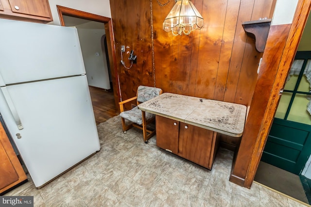 kitchen with brown cabinets, light countertops, freestanding refrigerator, and an inviting chandelier