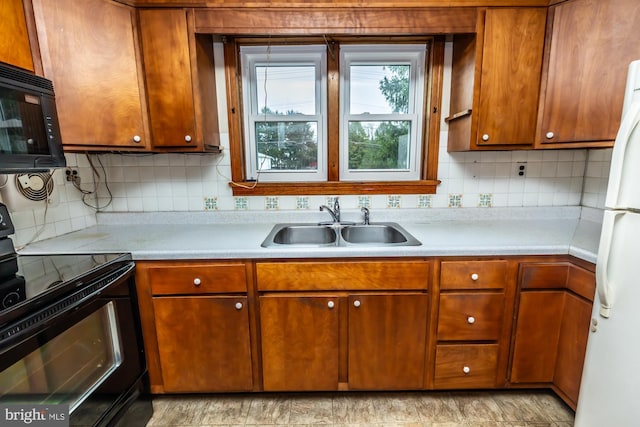 kitchen with a sink, backsplash, black appliances, and light countertops