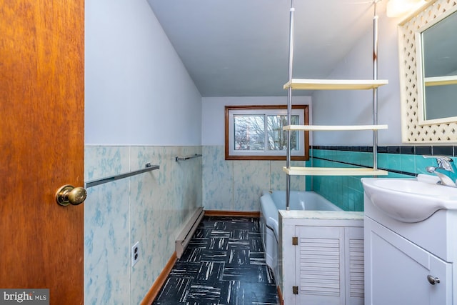 bathroom with a bath, a wainscoted wall, vanity, and a baseboard heating unit