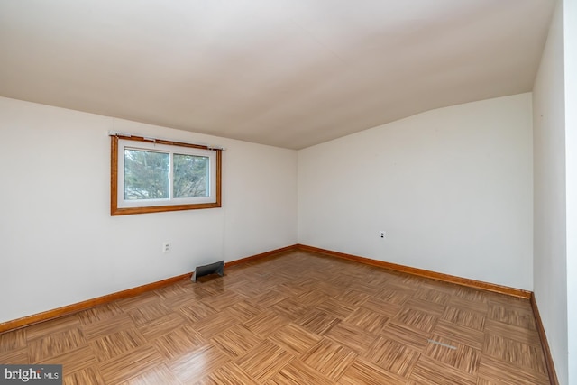 unfurnished room featuring baseboards and vaulted ceiling