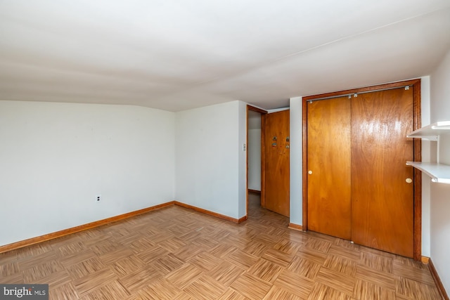 unfurnished bedroom featuring a closet, lofted ceiling, and baseboards