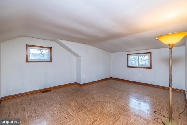 additional living space with a wealth of natural light, visible vents, baseboards, and vaulted ceiling