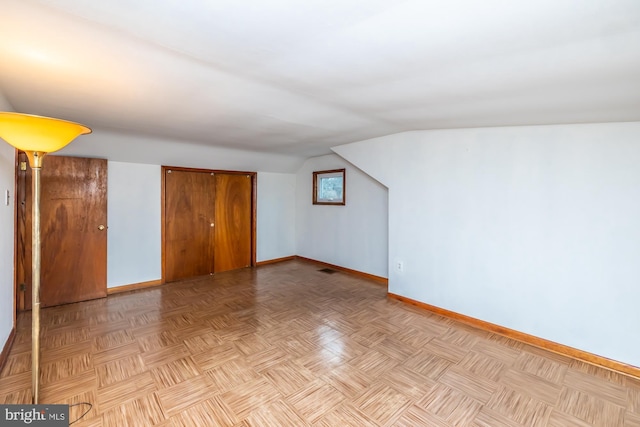 additional living space with baseboards and vaulted ceiling