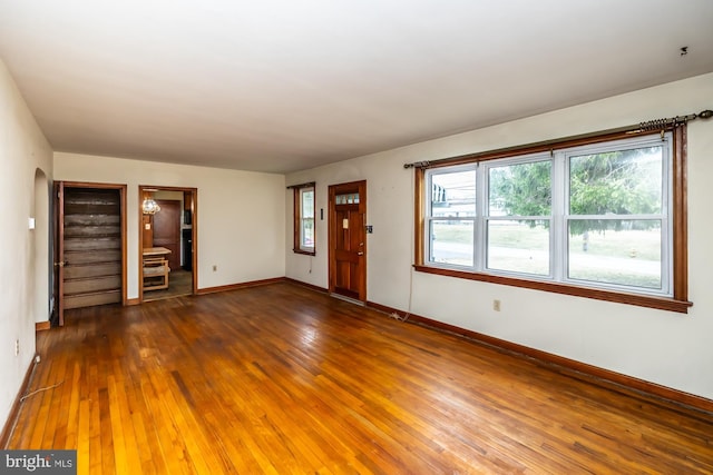 interior space with hardwood / wood-style floors, arched walkways, and baseboards