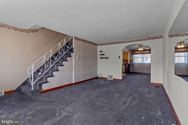 unfurnished living room featuring visible vents, stairway, arched walkways, a textured ceiling, and a ceiling fan