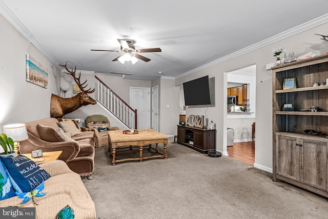 living room featuring baseboards, ornamental molding, stairs, ceiling fan, and light carpet