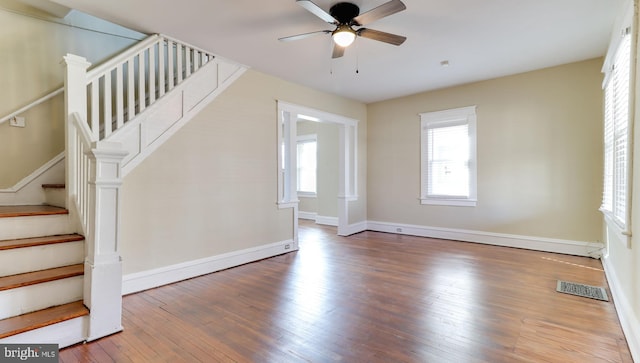 interior space featuring visible vents, wood-type flooring, baseboards, ceiling fan, and stairs